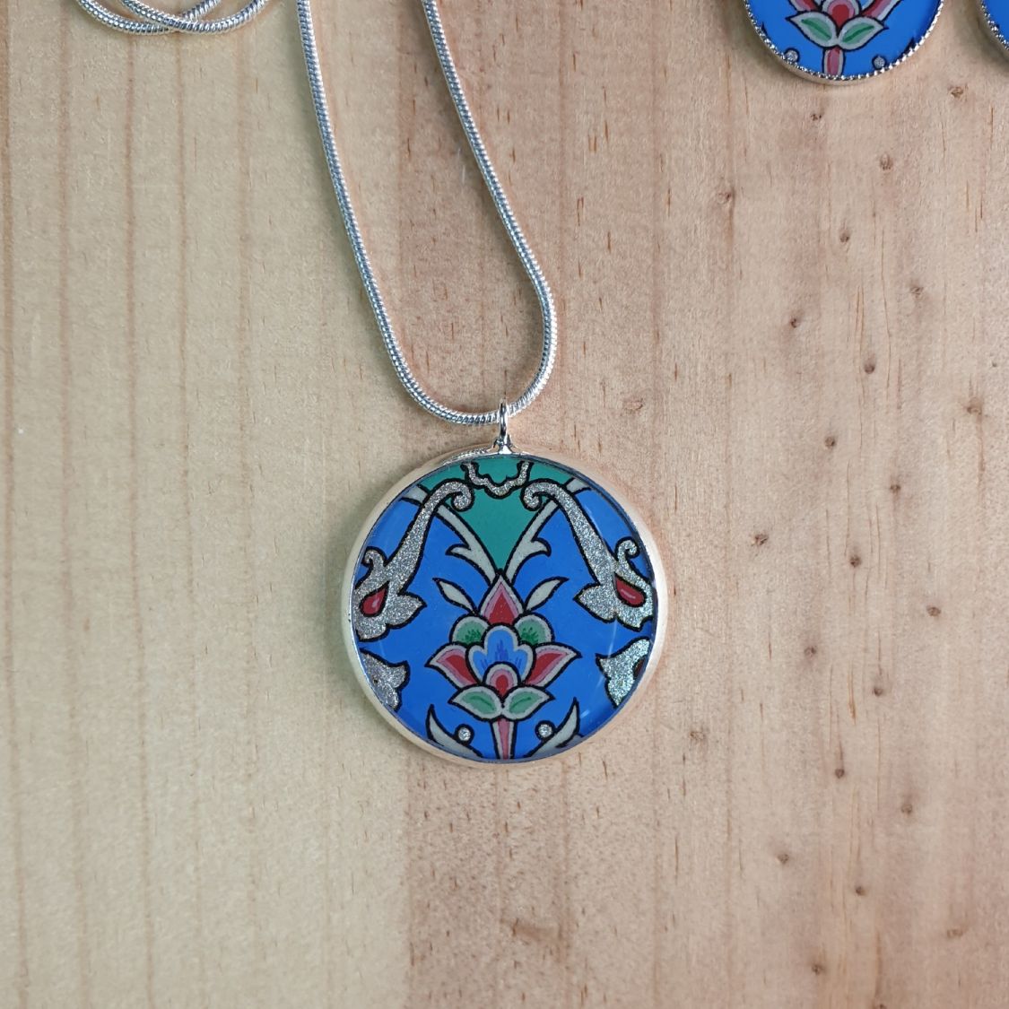 Collier pendentif fleur et arabesques bleu/argenté/vert/rosé sur chaîne argentée